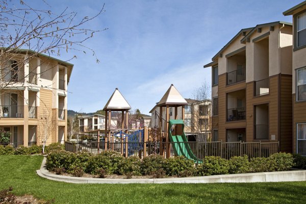 Playground with swings and slides at Acacia on Santa Rosa Creek Apartments, family-friendly outdoor space for residents