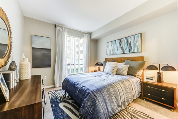 The Gallery at NoHo Commons: Cozy bedroom with modern decor and large windows in luxury apartments