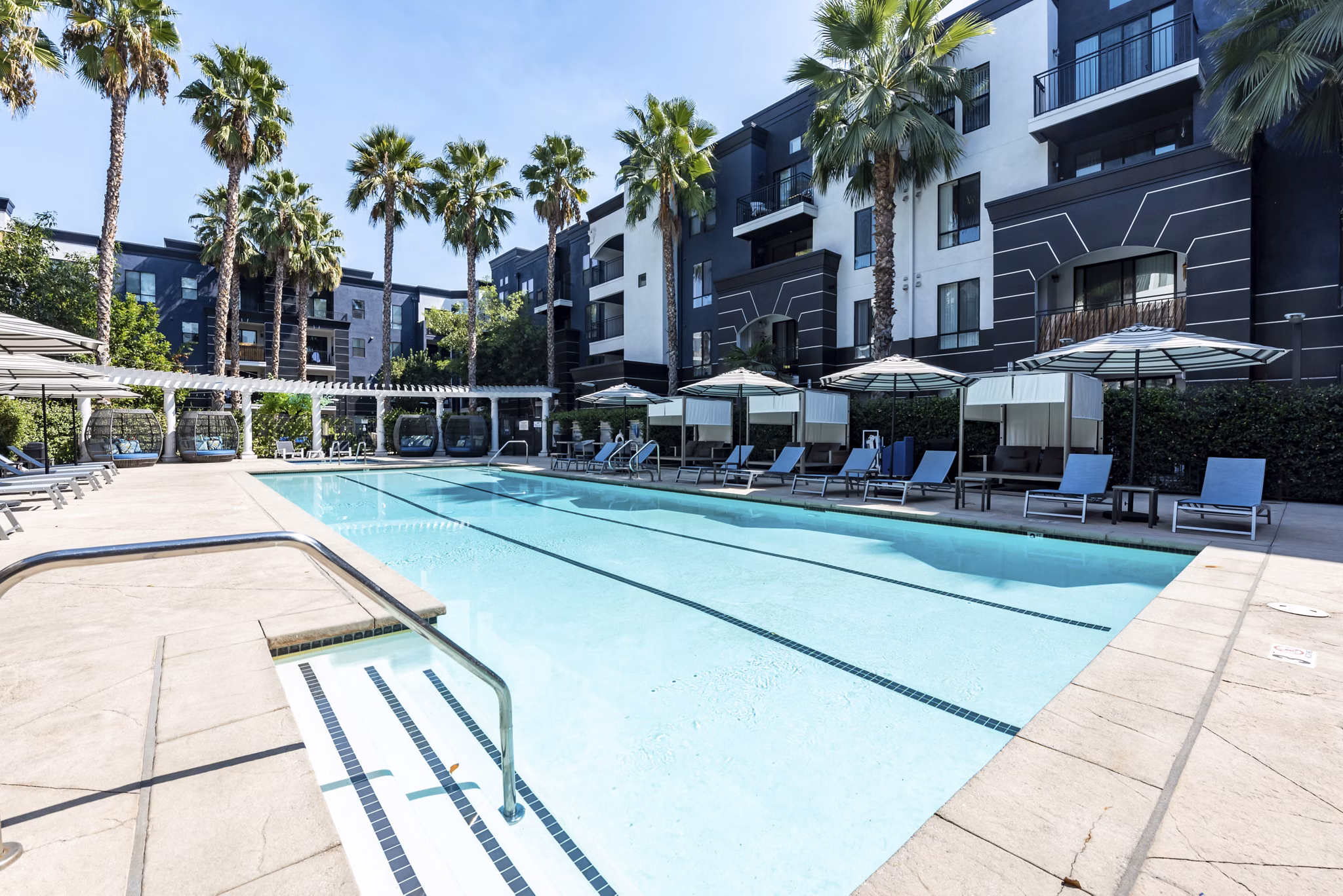 Luxurious pool area at The Gallery at NoHo Commons apartments, featuring stylish lounge chairs and vibrant landscaping for relaxation