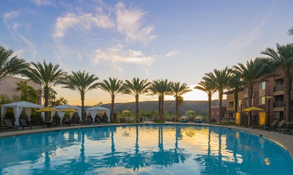 Luxurious pool area at The Verge Apartments with lounge seating and greenery, ideal for relaxation and socializing