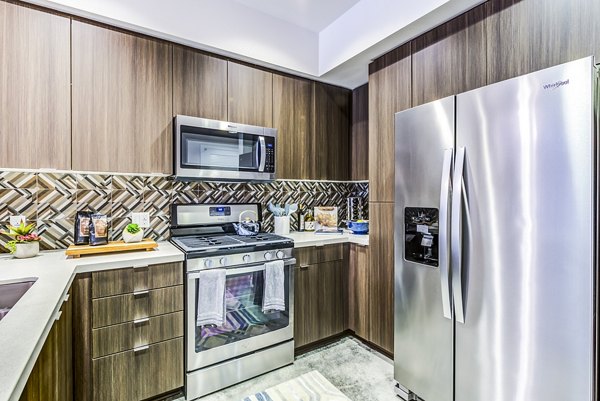 Modern kitchen with stainless steel appliances and quartz countertops in Luce Apartments, luxury living by Greystar