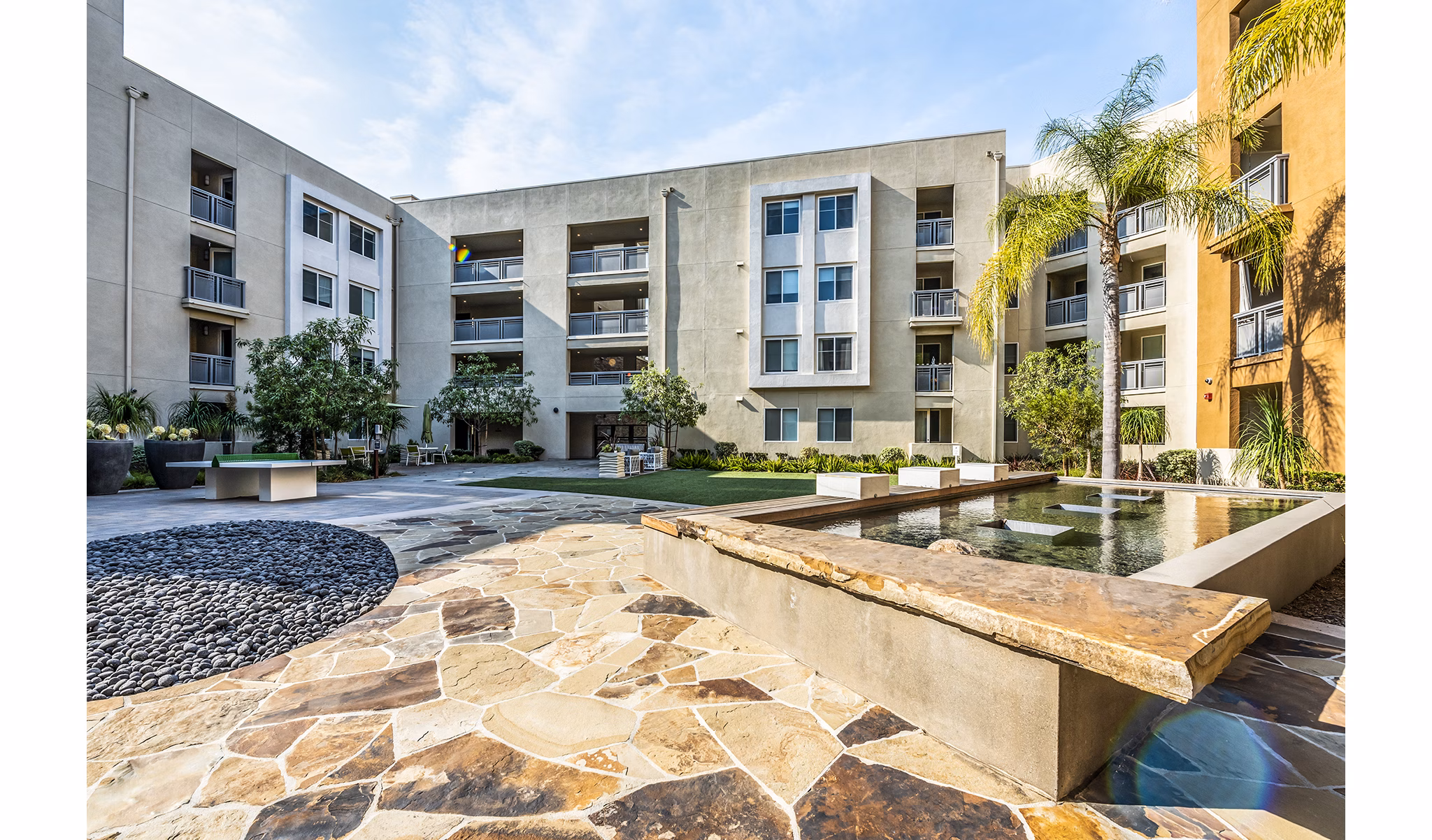 Lush green courtyard at Luce Apartments with seating areas, offering a serene outdoor space in a luxury community