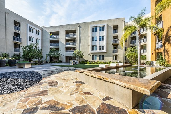 Lush green courtyard at Luce Apartments with seating areas, offering a serene outdoor space in a luxury community