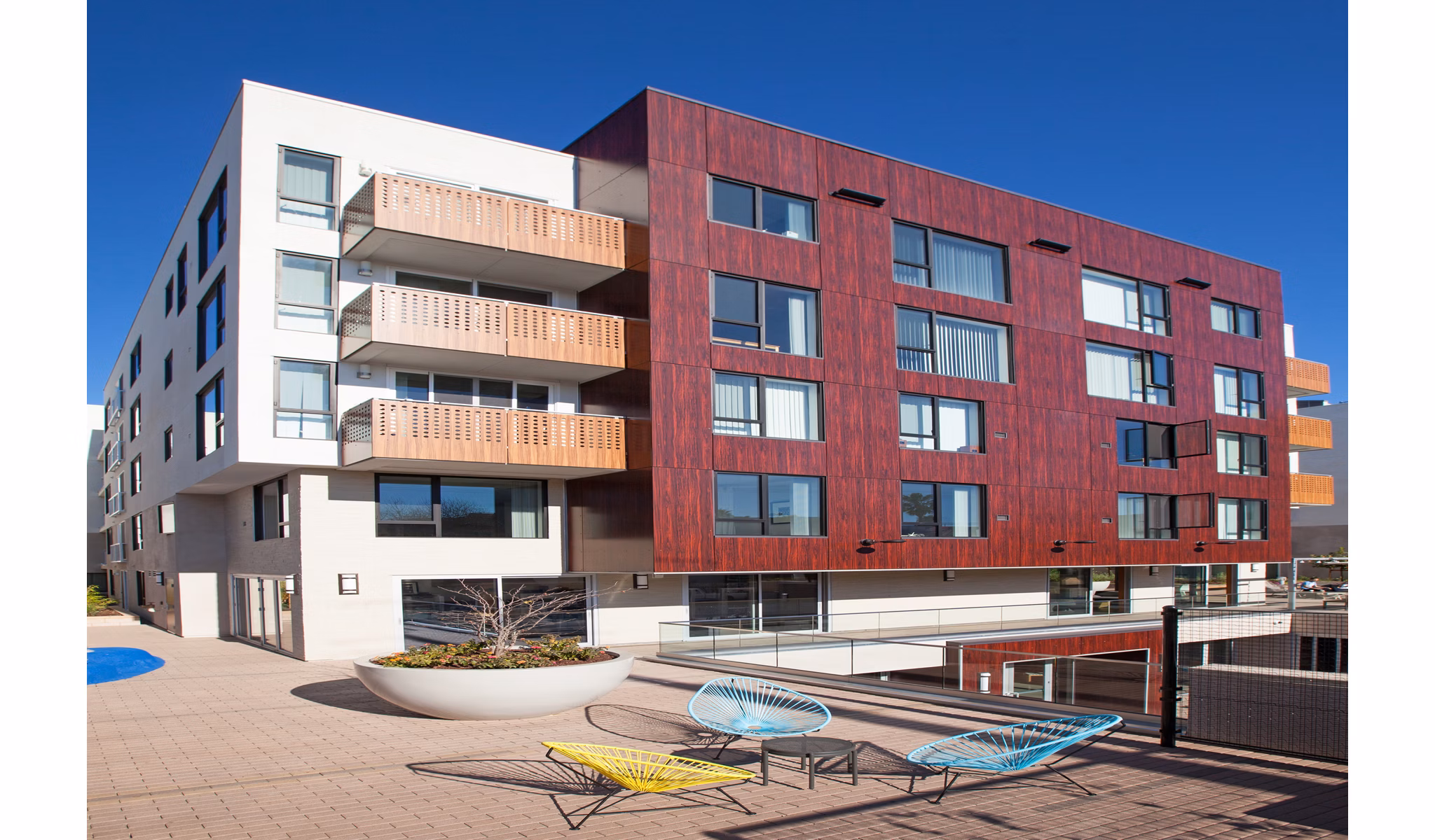 Modern luxury apartment building with balconies and a patio area in a vibrant city setting