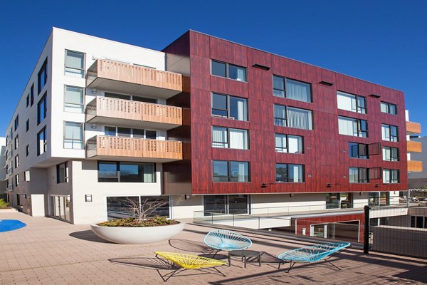 Modern luxury apartment building with balconies and a patio area in a vibrant city setting