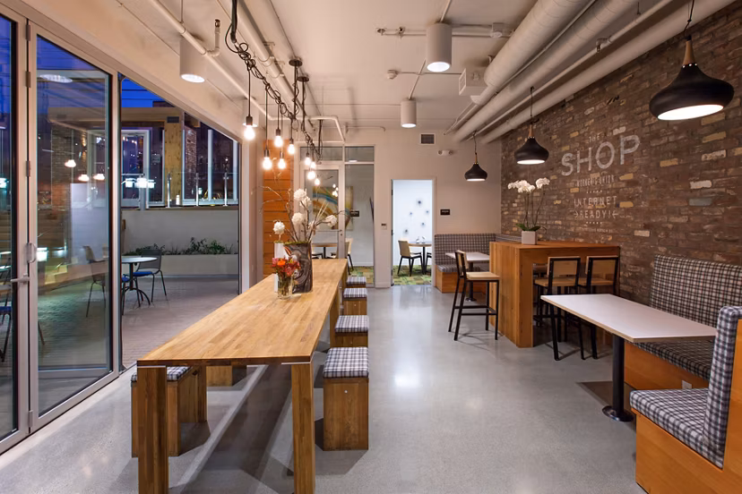 Modern dining area with wooden tables and pendant lighting in luxury apartments, featuring decorative flowers and a stylish brick wall