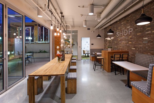 Modern dining area with wooden tables and pendant lighting in luxury apartments, featuring decorative flowers and a stylish brick wall