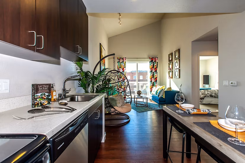 Modern kitchen and living area featuring dark cabinets and a cozy dining setup in luxury apartments