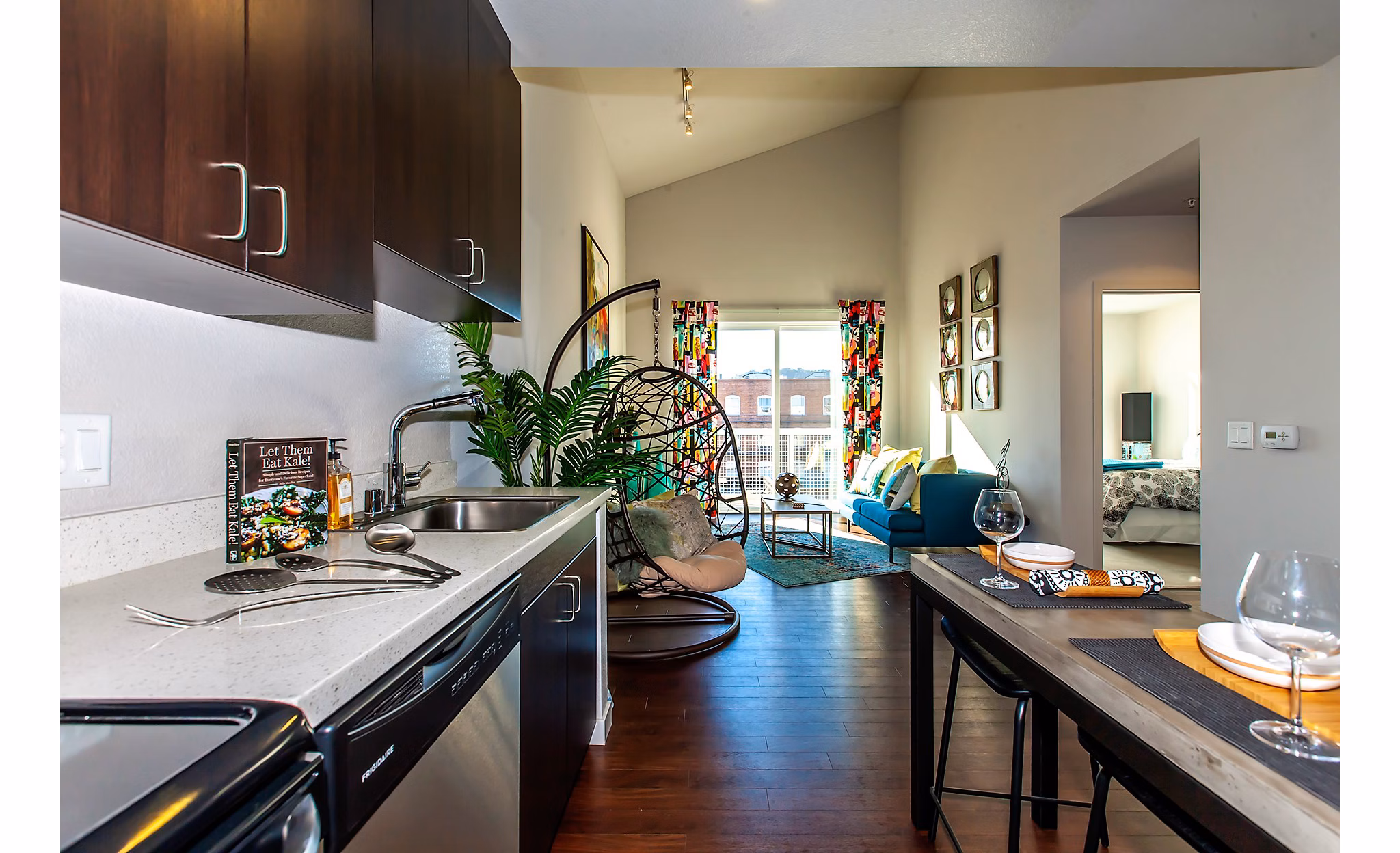 Modern kitchen and living area featuring dark cabinets and a cozy dining setup in luxury apartments
