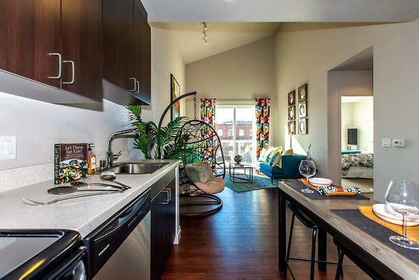 Modern kitchen and living area featuring dark cabinets and a cozy dining setup in luxury apartments