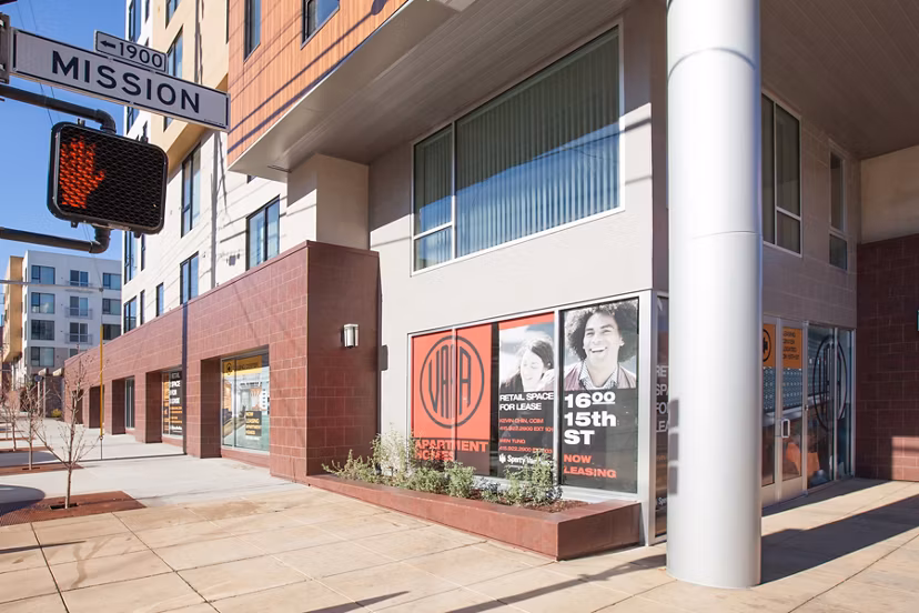 Retail spaces available for lease at a street corner building with a Mission street sign and traffic light