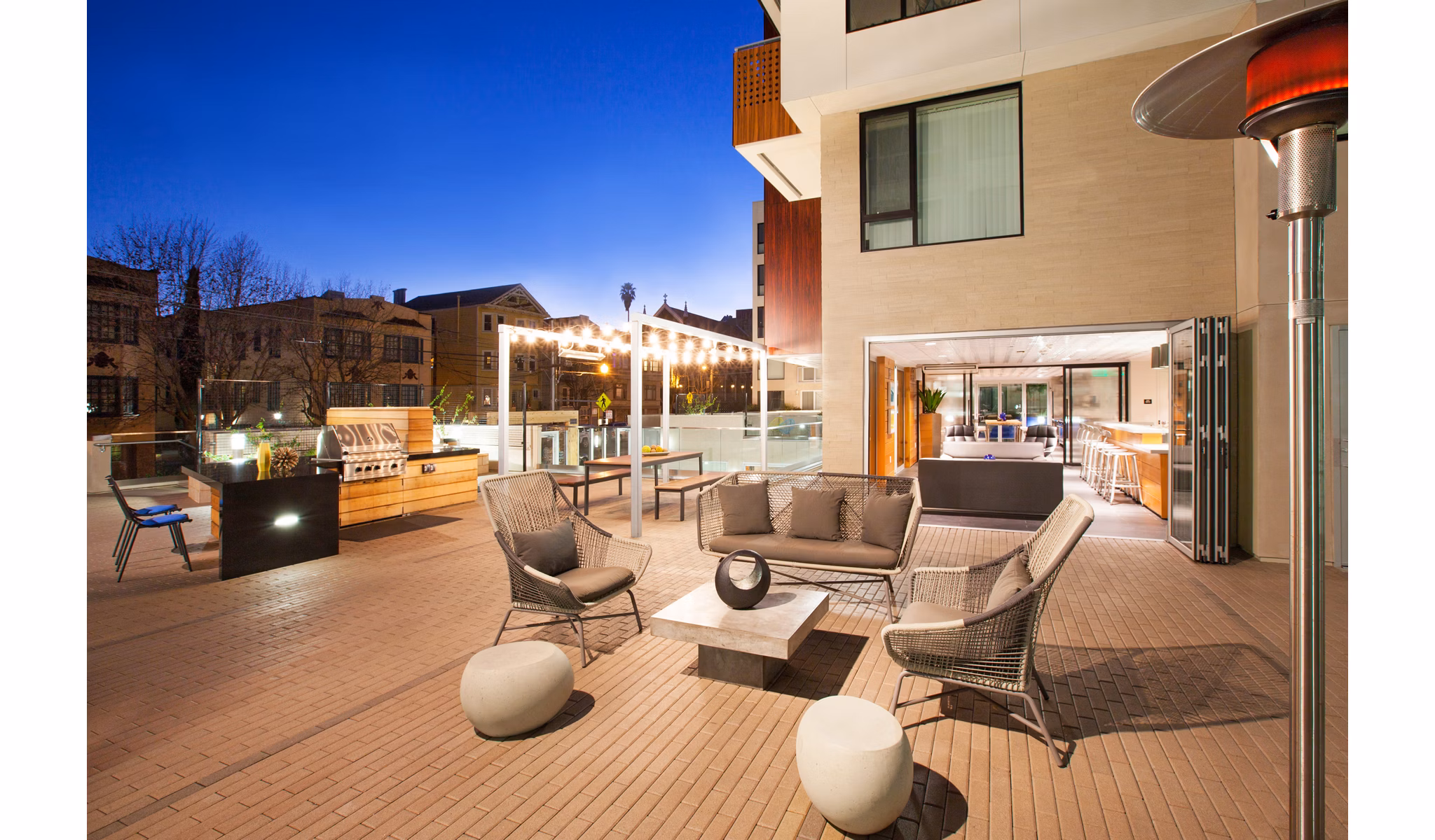 Outdoor patio area with seating, tables, and a grill at luxury apartments
