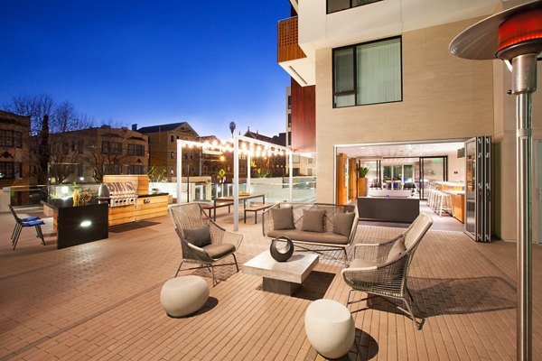 Outdoor patio area with seating, tables, and a grill at luxury apartments