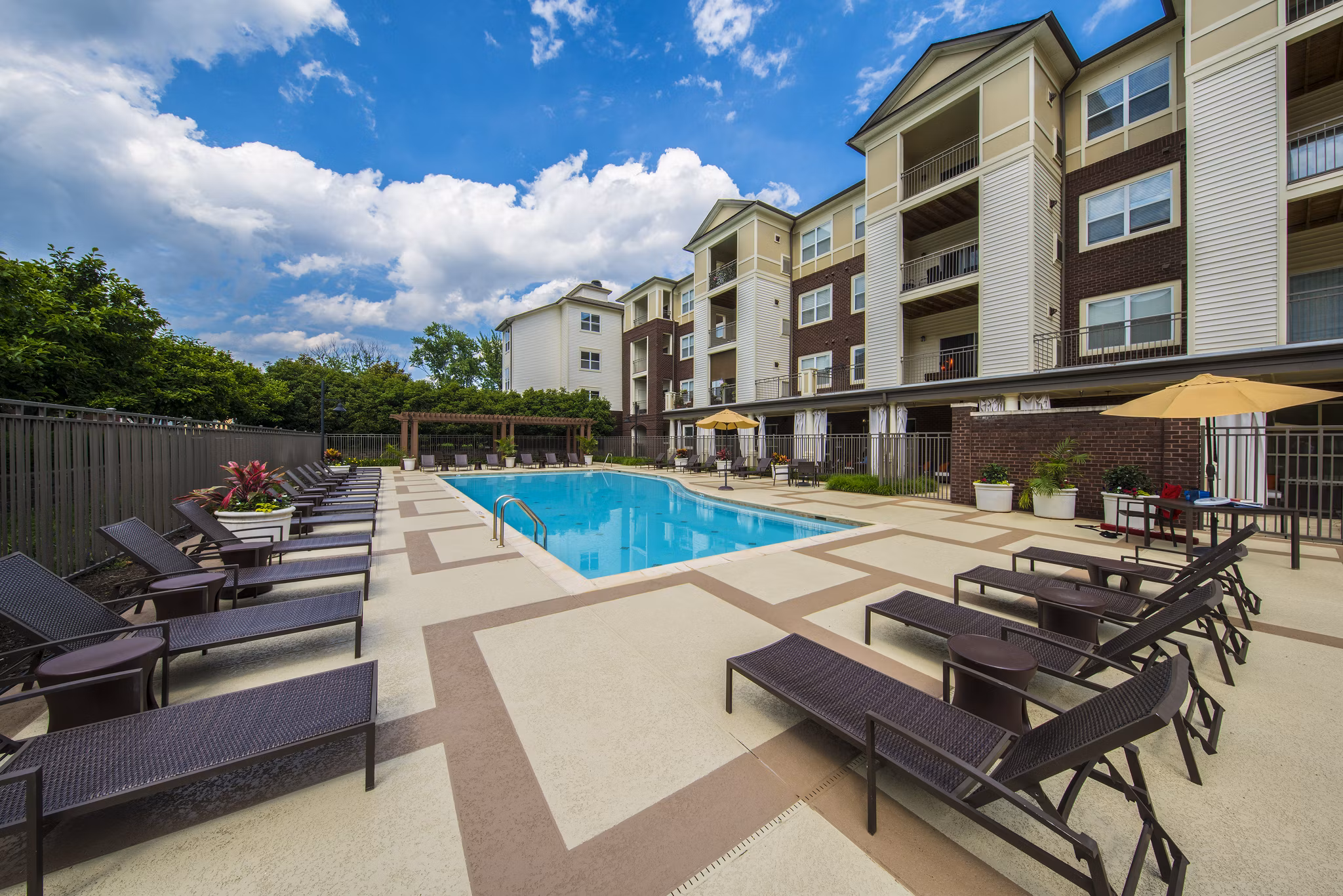 Sunlit outdoor pool at Bailey's Crossing Apartments with lounge chairs and landscaping