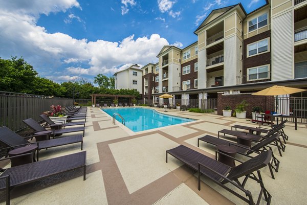 Sunlit outdoor pool at Bailey's Crossing Apartments with lounge chairs and landscaping