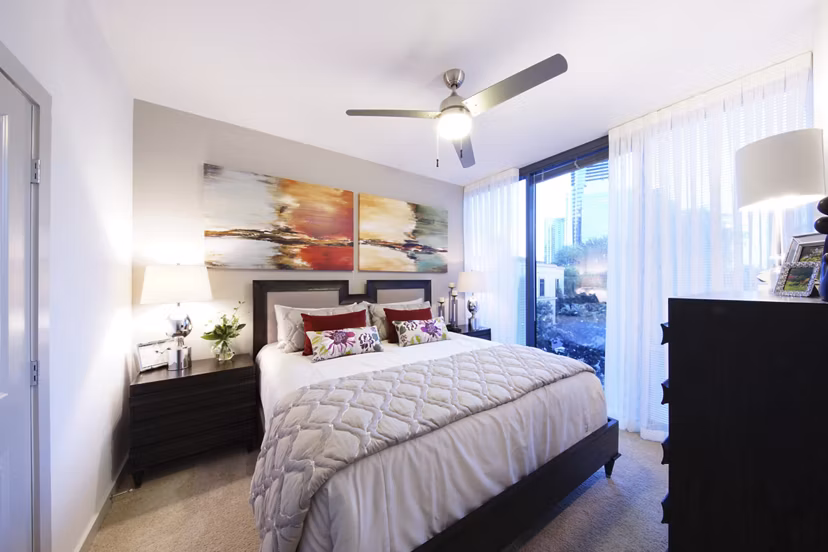 Modern bedroom featuring a bed, nightstands, and artwork with sheer curtains in luxury apartments