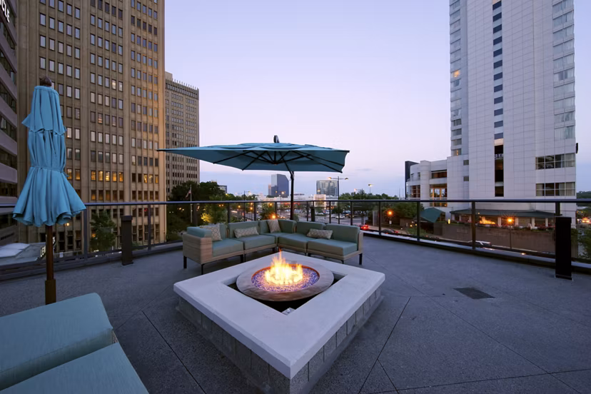 Rooftop patio with fire pit and outdoor seating in luxury apartments surrounded by city skyline