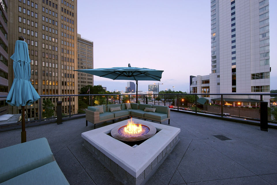 Rooftop patio with fire pit and outdoor seating in luxury apartments surrounded by city skyline
