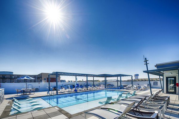 Allegro Apartments: Luxurious pool area with lounge chairs and umbrellas in vibrant community atmosphere