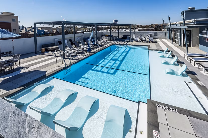 Allegro Apartments: Stunning resort-style pool area with lounge chairs and greenery in a serene setting