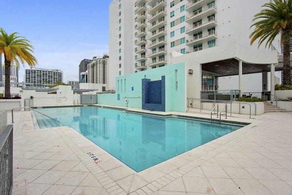 Relaxing pool area at SoMa at Brickell Apartments with modern lounge seating and lush greenery
