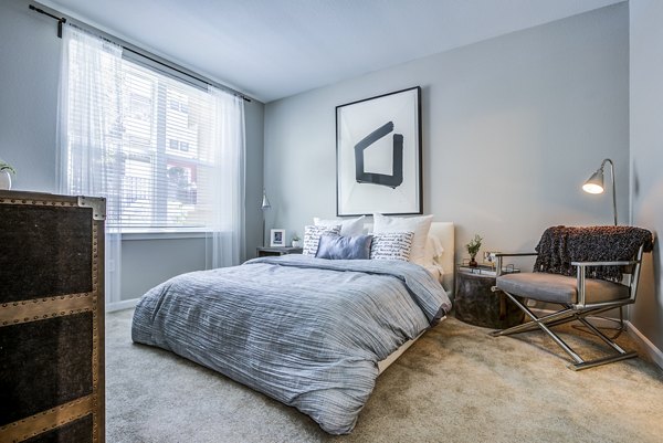 Cozy bedroom with modern furnishings in Acappella Apartments, luxury living option offered by Greystar