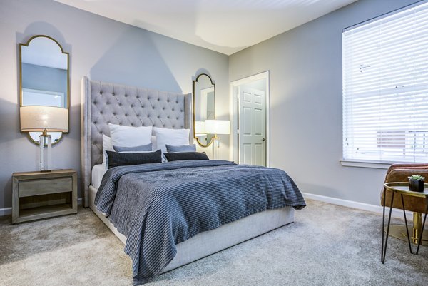 Bedroom with large windows and modern decor at Acappella Apartments