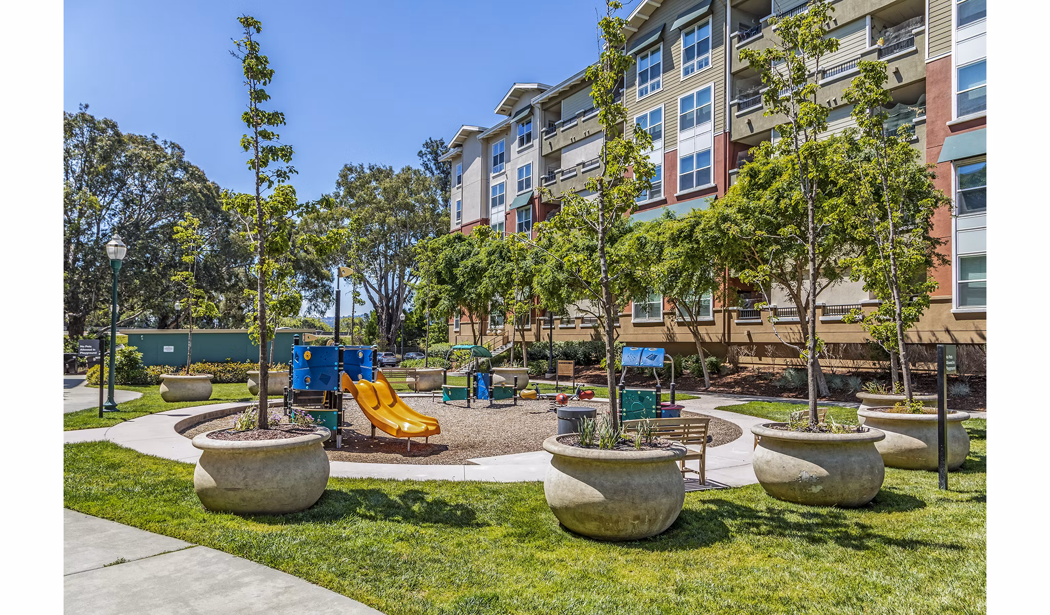 Acappella Apartments: Modern playground with slides and swings in family-friendly setting