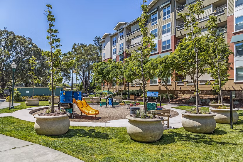 Acappella Apartments: Modern playground with slides and swings in family-friendly setting