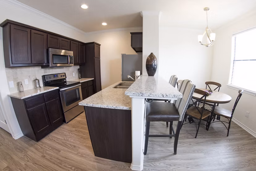 Modern kitchen featuring stainless steel appliances and granite countertops in Camber Villas' luxury apartments