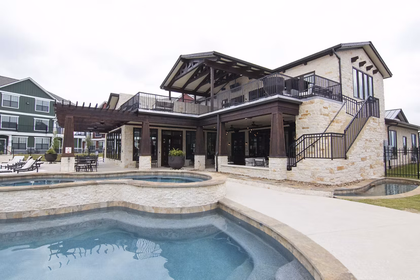 Elegant poolside oasis at Camber Villas Apartments featuring lounge chairs and lush landscaping
