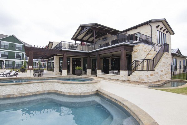 Elegant poolside oasis at Camber Villas Apartments featuring lounge chairs and lush landscaping