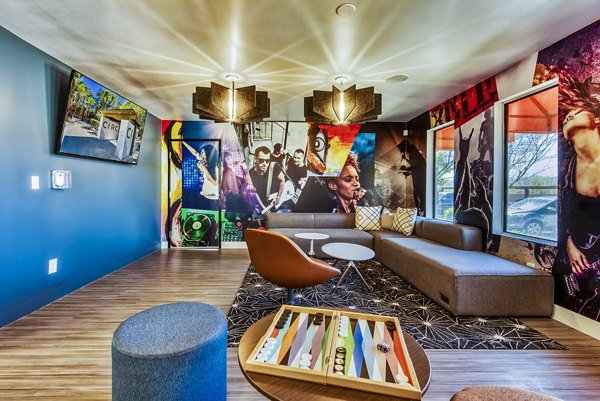 Modern lounge area with colorful wall art, seating, and a backgammon board at luxury apartments