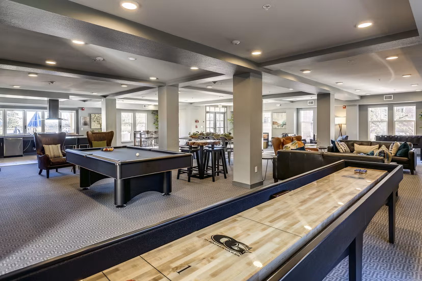 Game room with modern pool table and cozy seating area in Shorewood Heights Apartments, offering luxury community amenities for relaxation and entertainment