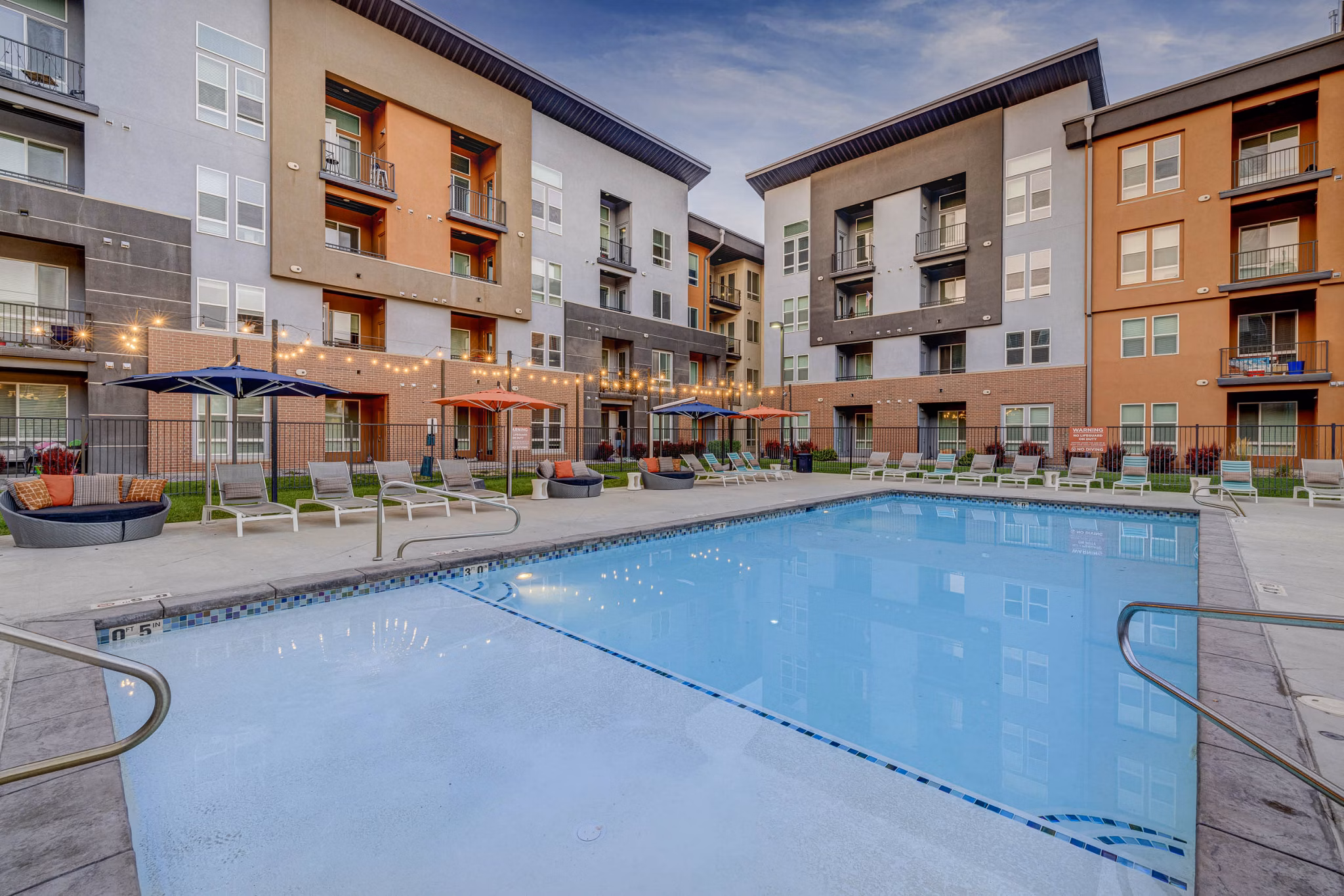 Resort-style pool at Novi at Jordan Valley Station Apartments with lounge chairs and lush landscaping