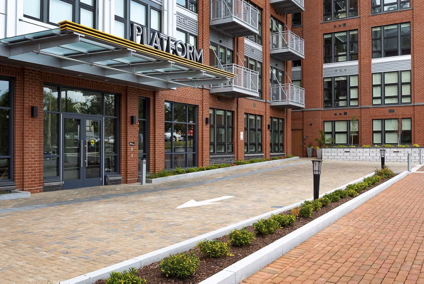 PLATFORM: Sleek modern apartment building with landscaped grounds and balconies in an urban setting
