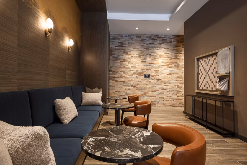 Modern lounge area with cushioned seating and marble tables, featuring a stylish brick accent wall