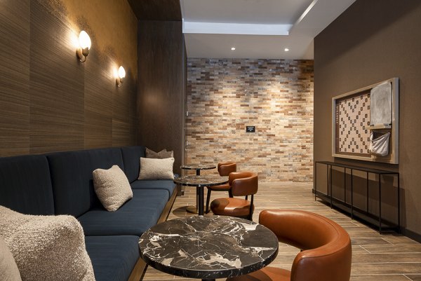 Modern lounge area with cushioned seating and marble tables, featuring a stylish brick accent wall