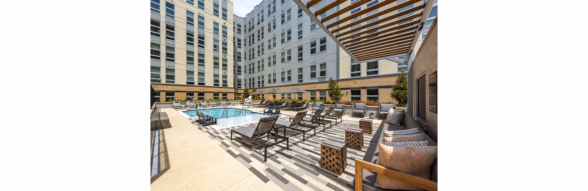 Outdoor pool area with lounge chairs and umbrellas at luxury apartments in a serene environment