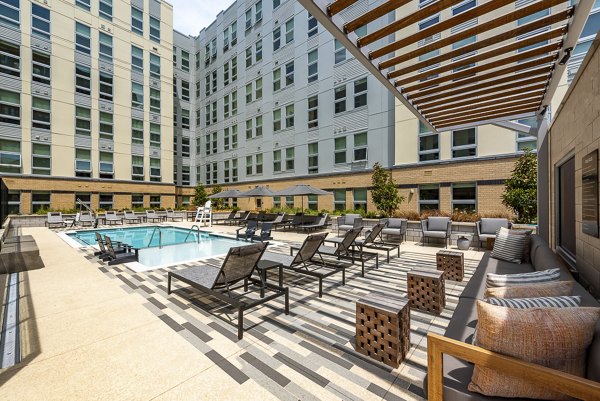 Outdoor pool area with lounge chairs and umbrellas at luxury apartments in a serene environment