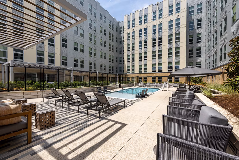 Outdoor pool area with lounge chairs and seating in luxury apartments courtyard