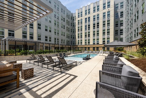 Outdoor pool area with lounge chairs and seating in luxury apartments courtyard