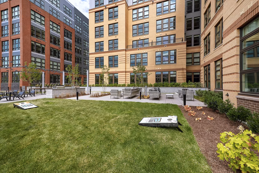 Outdoor gathering space with grassy lawn and cornhole boards at luxury apartments