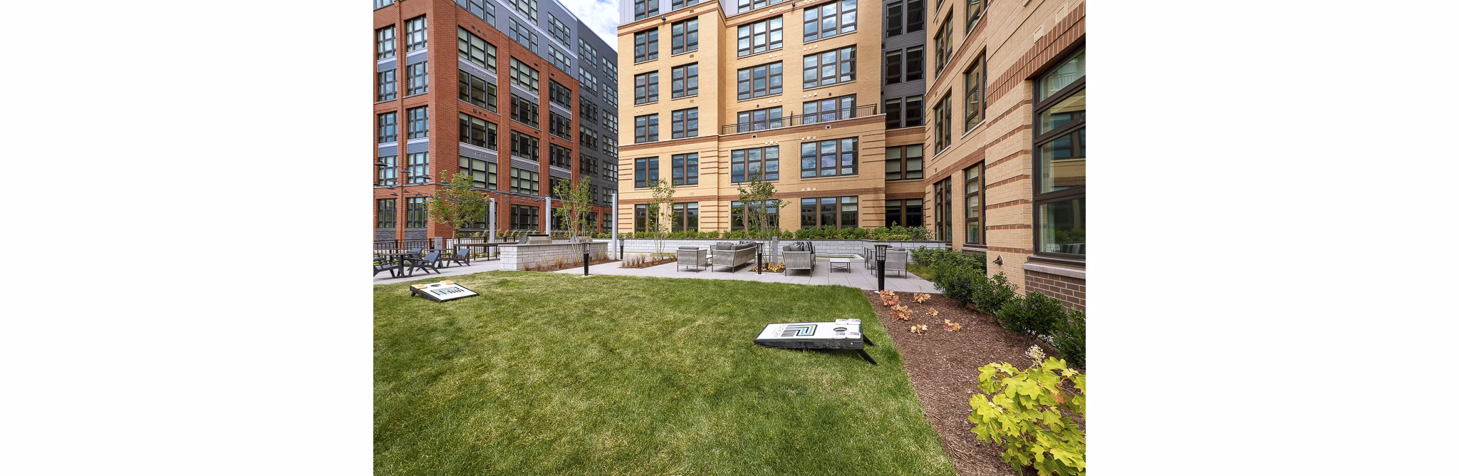 Outdoor gathering space with grassy lawn and cornhole boards at luxury apartments