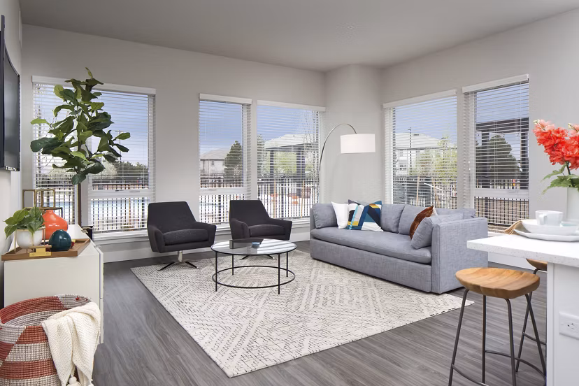 Spacious living room with modern decor at The Glenn Apartments, featuring hardwood floors and large windows for natural light