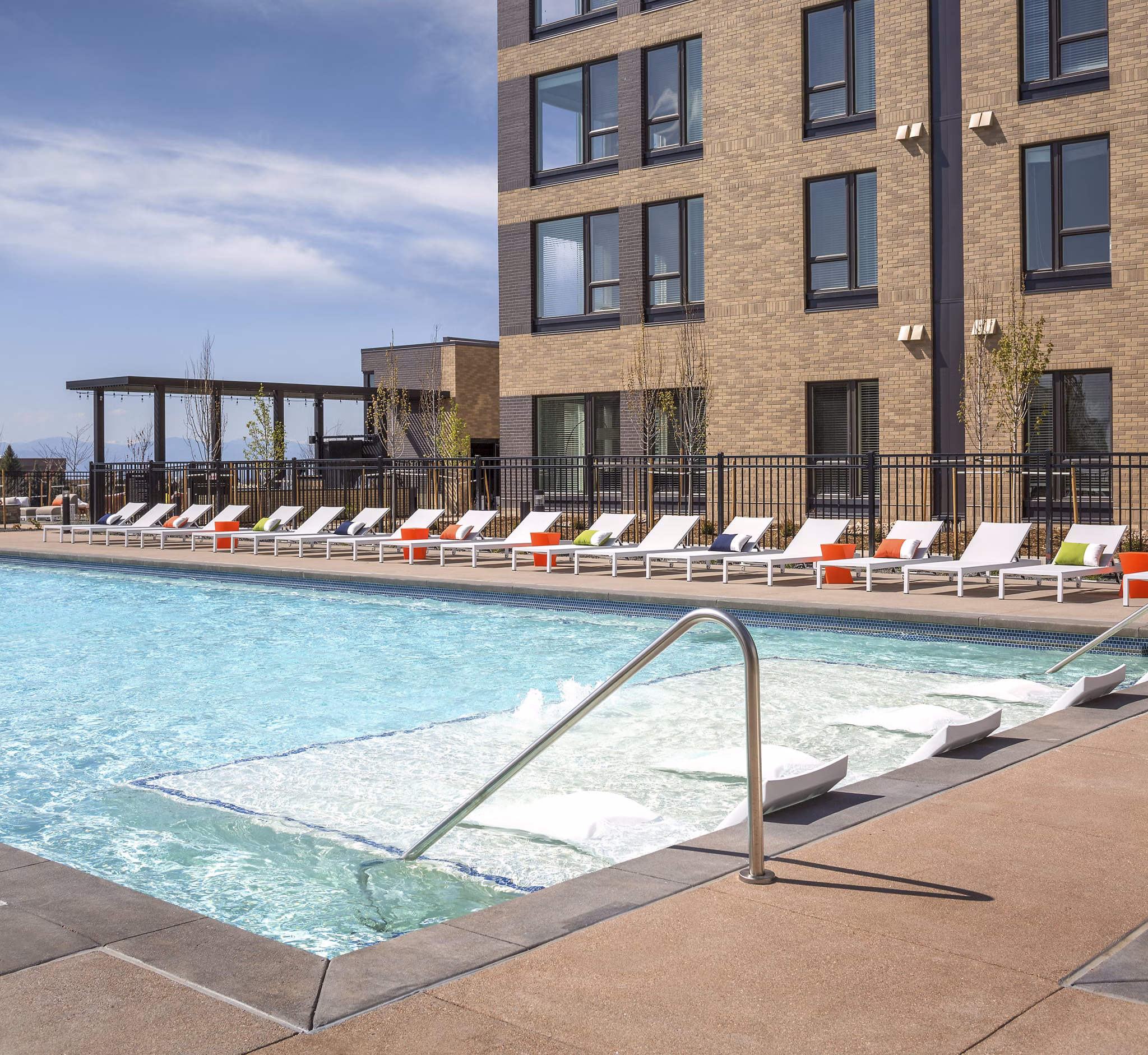 Sparkling outdoor pool at The Glenn Apartments with lounge seating, perfect for relaxation and leisure activities in a luxury setting
