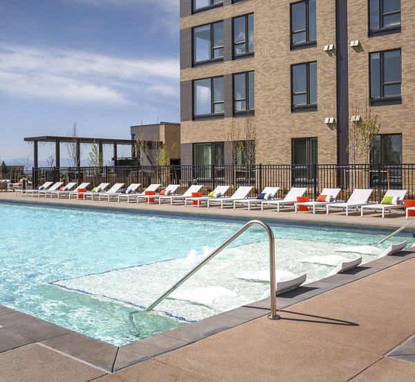 Sparkling outdoor pool at The Glenn Apartments with lounge seating, perfect for relaxation and leisure activities in a luxury setting