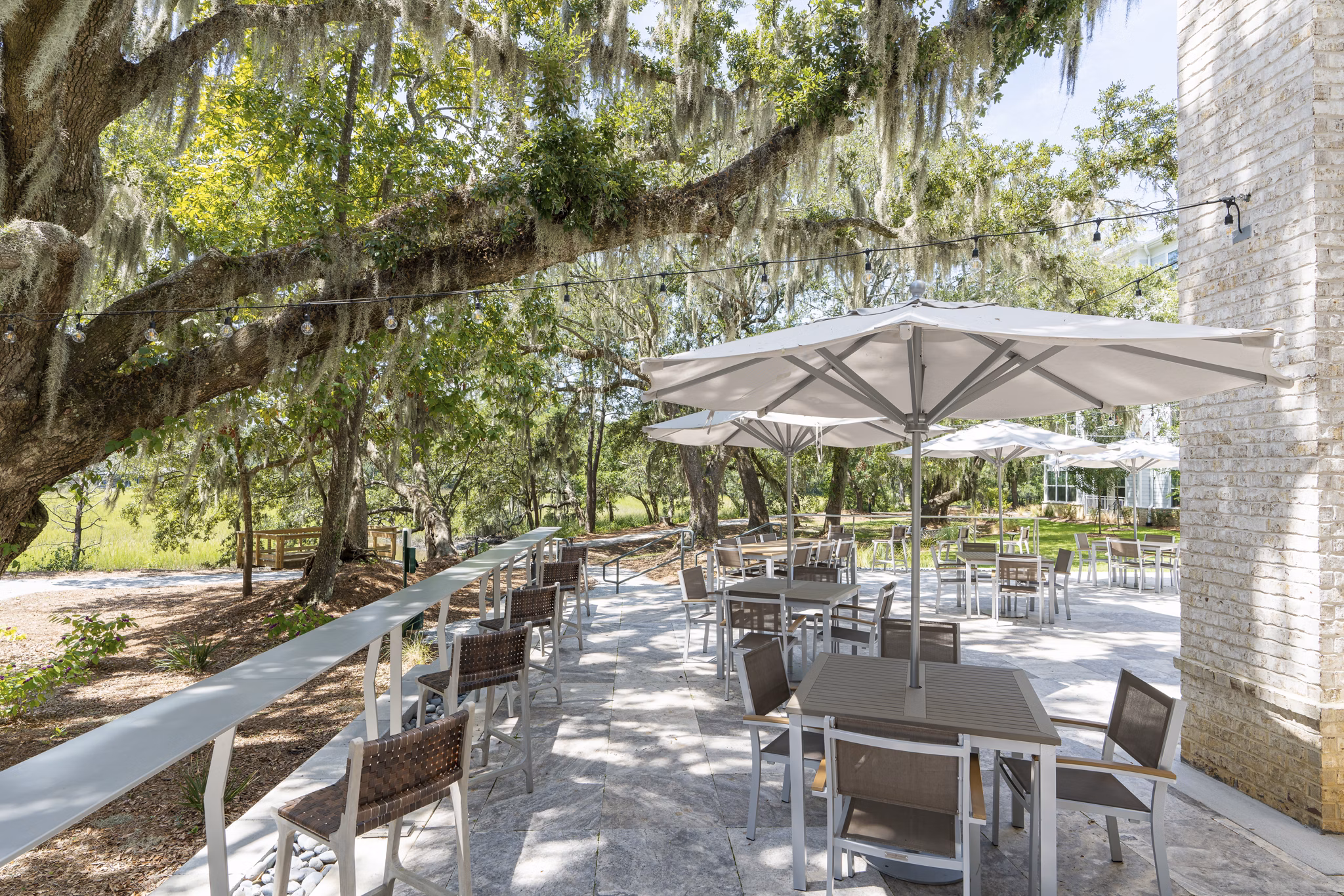 Outdoor patio with modern seating at Overture West Ashley Apartments, featuring lush greenery and ambient lighting
