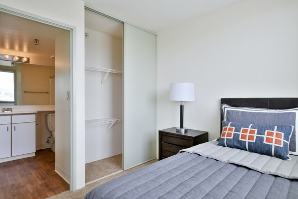 The Fillmore Center Apartments: Cozy bedroom with modern decor and city skyline views