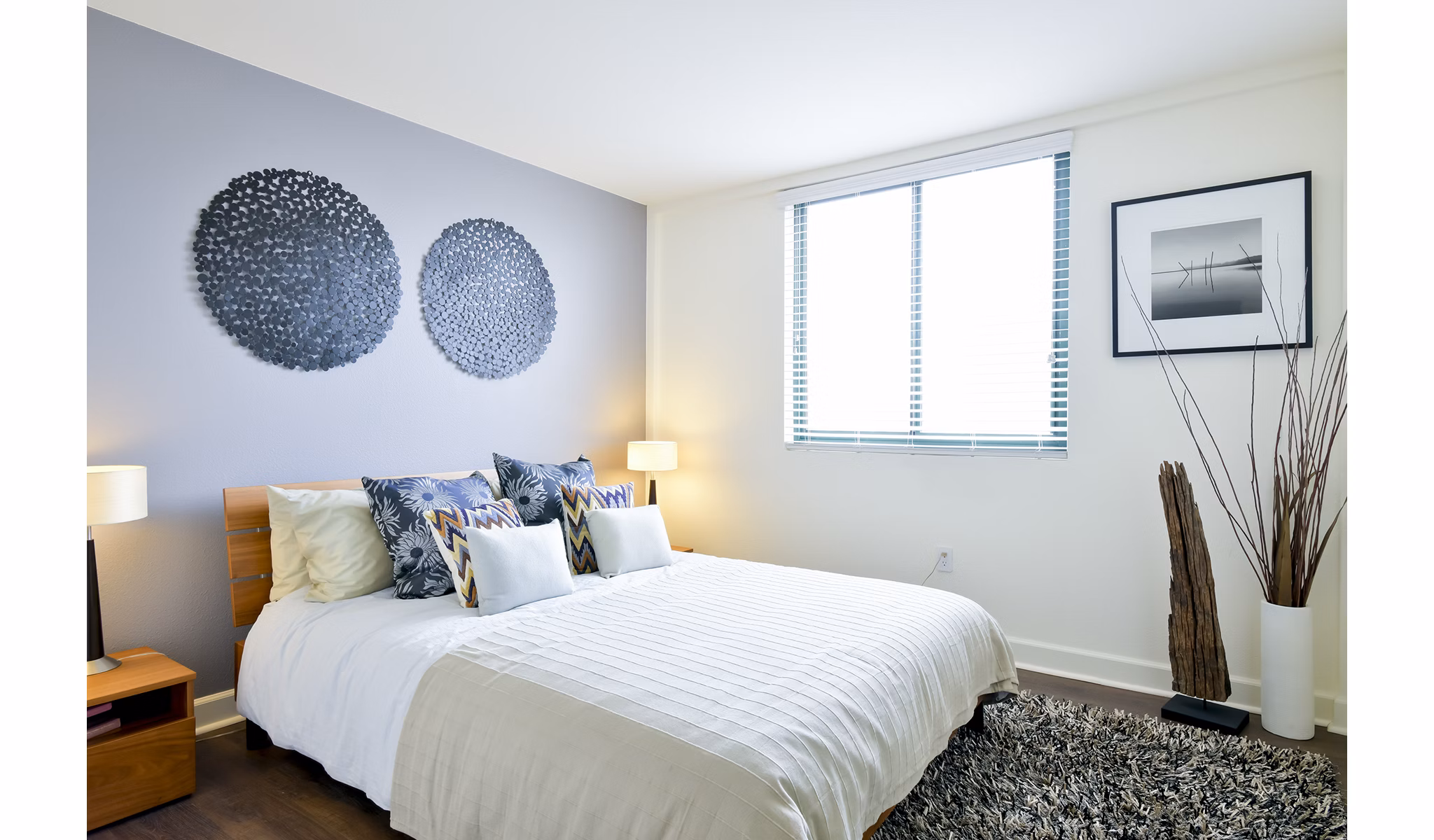 Spacious bedroom with modern furnishings at The Fillmore Center Apartments featuring stylish decor and ample lighting